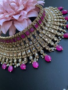 This choker is sure to be a complete statement look for your next event! made with gorgeous polki stones with antique gold finish and a pop of color with pink/purple beads, this choker is sure to be the perfect addition for your next occasion! comes with matching earrings and tikka! Pink Kundan Necklace For Reception In Temple Jewelry Style, Pink Kundan Choker For Party, Pink Temple Jewelry Bridal Necklace For Reception, Pink Choker For Party And Festivals, Pink Party Choker For Festivals, Pink Kundan Choker Necklace For Party, Pink Kundan Choker For Festivals, Pink Kundan Choker Necklace For Festive Occasions, Pink Kundan Necklace With Meenakari For Reception