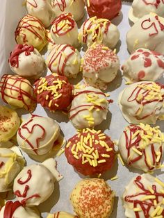 a box filled with lots of different colored cupcakes covered in white and red icing