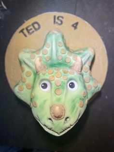 there is a green and yellow ceramic animal head on the wall next to a sign that says ted is 4