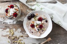 a bowl of oatmeal topped with cherries and nuts next to a spoon