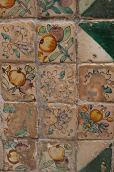 an artisticly painted tile wall with flowers and leaves on the bottom, along with other tiles