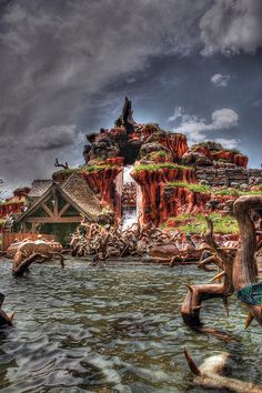 an image of a waterfall coming out of the water with people swimming in it and onlookers watching