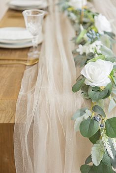 the table is set with white flowers and greenery