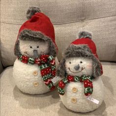 two snowmen with hats and scarves on their heads are sitting on a couch