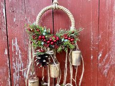 christmas decorations hanging on a red wooden wall with bells and pineconis in them