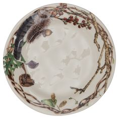 a white plate with branches, leaves and an owl's head on it is shown