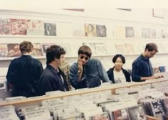 a group of people standing in front of a store counter with cds on the shelves