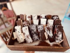 a wooden tray filled with different types of cowhides on top of each other