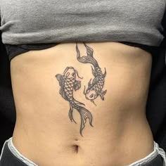 a woman's stomach with two koi fish tattoo on the lower part of her belly