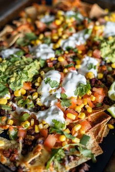 a tray filled with nachos topped with sour cream and toppings on top of tortilla chips