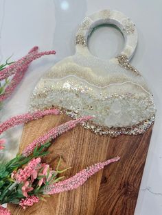 a white purse sitting on top of a wooden board next to pink flowers and greenery