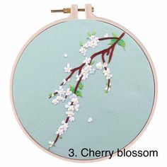 the embroidery pattern is in three different colors and has white flowers on it, along with green leaves