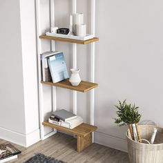 a wooden shelf with books and magazines on it next to a plant in a basket