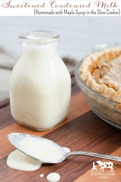 a wooden cutting board topped with a pie next to a bottle of milk and a spoon