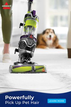 a person with a dog laying on the floor next to a vacuum cleaner that is cleaning