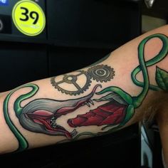 a man with a tattoo on his arm has a green snake wrapped around the wrist