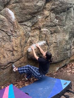 a man climbing up the side of a large rock with his feet in the air