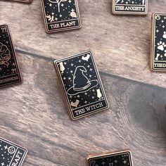 some black and white pin badges on a wooden table with stars, witches and the word'the plant '