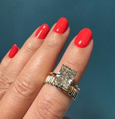 a woman's hand with red nail polish and an engagement ring on her finger