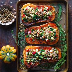 baked sweet potatoes with vegetables and herbs on a baking sheet next to pumpkins, seeds and squash