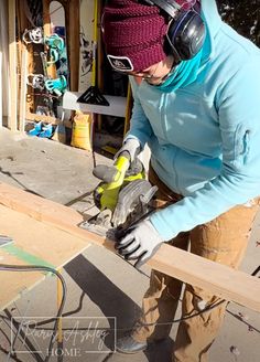 a woman working on wood with a pair of gloves and headphones in her hands