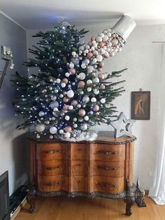 a decorated christmas tree on top of a dresser in the corner of a living room