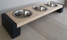 three stainless steel bowls sit on a wooden bench