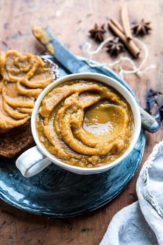 there is a cup of coffee and some bread on the plate with cinnamon sticks next to it