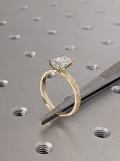 a diamond ring sitting on top of a piece of metal next to a pair of scissors