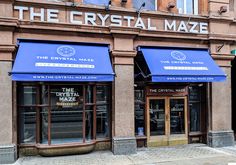 the crystal maze is located on the corner of an old brick building with blue awnings