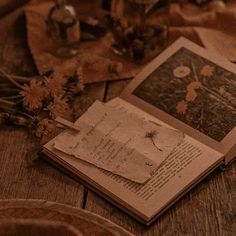 an open book sitting on top of a wooden table next to flowers and other items