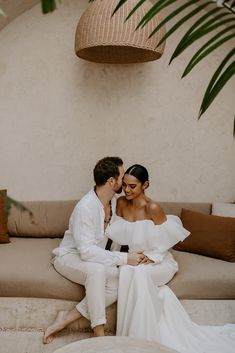 a man and woman sitting on a couch next to each other in front of a plant