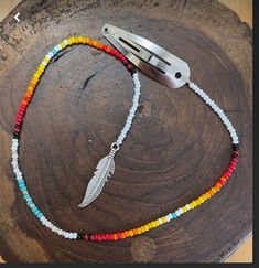 a multicolored beaded necklace with a knife on top of it and a piece of wood in the background