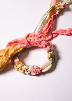 three scarves are tied together on a white surface, one is pink and the other is yellow