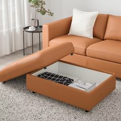 an orange leather couch with a coffee table in the middle and a white pillow on top