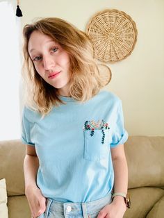 a woman standing in front of a couch with her hand on her hip and looking at the camera