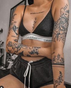 a woman with tattoos on her arm and chest is sitting in front of a mirror