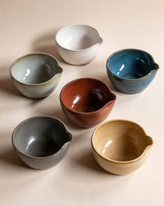 five different colored bowls sitting next to each other