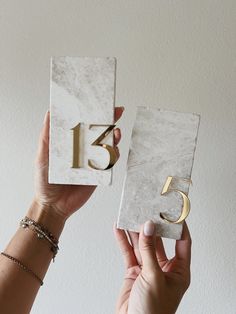 two hands holding up marble blocks with the number fifteen and five in gold on them