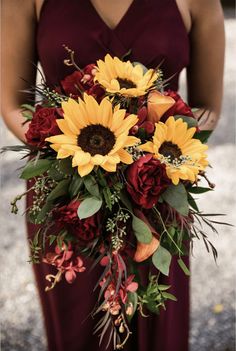 a bridesmaid holding a bouquet of sunflowers and red roses in her hand