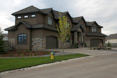 a large brown house with two garages and a yellow fire hydrant