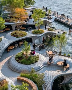 people are sitting at tables on the edge of a body of water with benches and trees