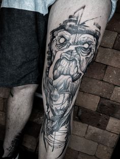 a man's leg with a black and white tattoo design on it, including an image of a demon