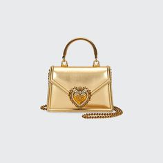 Dolce&Gabbana "Devotion" top-handle bag in metallic leather. Filigreed shoulder chain. Flap top with sacred heart embellishment. 5.1"H x 7.5"W x 1.8"D. Made in Italy. Gold Party Bag With Metal Logo, Gold Party Bags With Metal Logo, Shoulder Chain, Sacred Heart, Handle Bag, Metallic Leather, Leather Top, Top Handle, Dolce And Gabbana