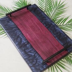 a notebook covered in blue and red paper next to a palm leaf on a white surface