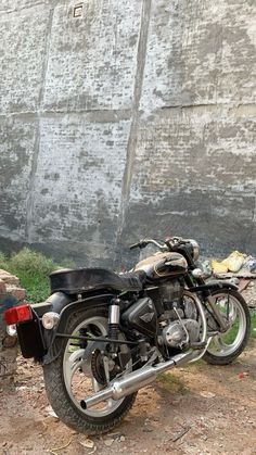 a black motorcycle parked next to a stone wall