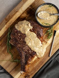 a piece of steak covered in gravy on a cutting board