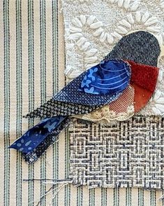 two colorful birds sitting on top of a piece of fabric