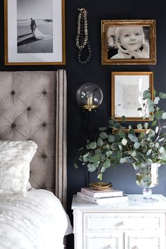 a bedroom with black walls and pictures on the wall, including a white bed headboard