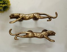 two metal cheetah wall hooks sitting on top of a table